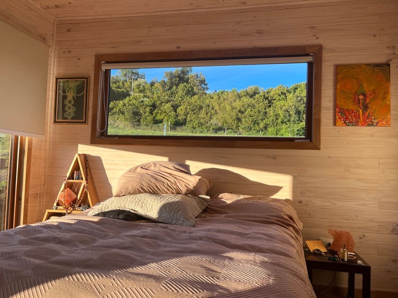 Dormitorio principal con cama doble y ventana al bosque