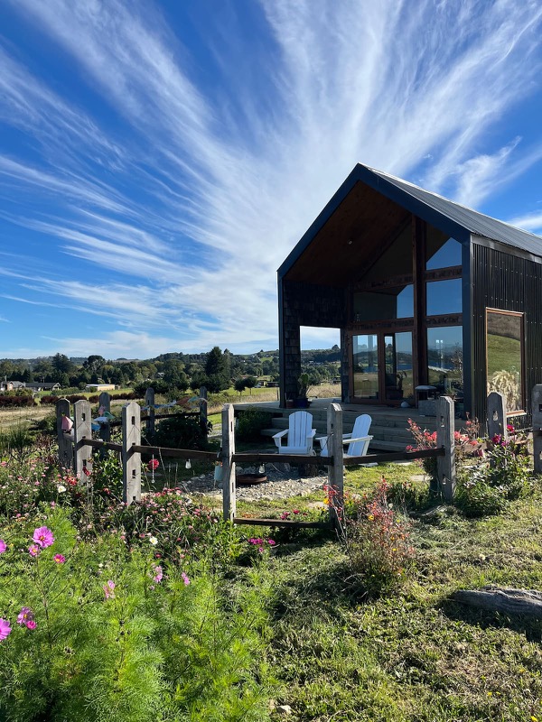La casa-galpón negra con su terraza y el jardín